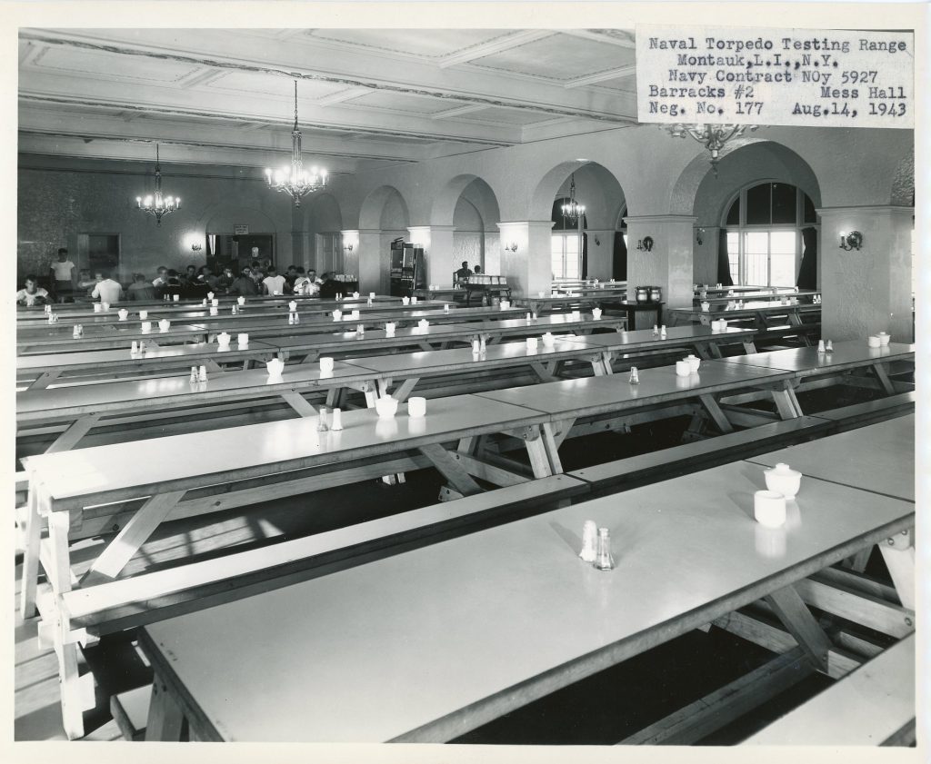 Cafeteria style tables in rows an army mess hall.