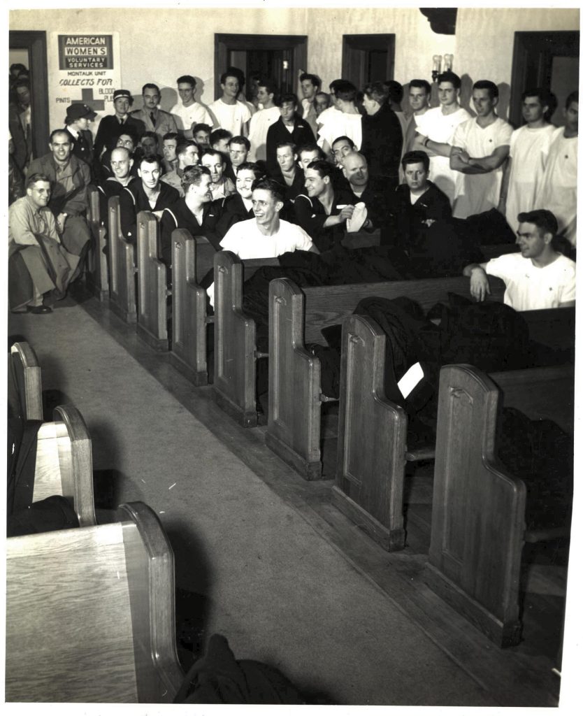 Soldiers in white T-shirts sit in church pews at a blood drive.