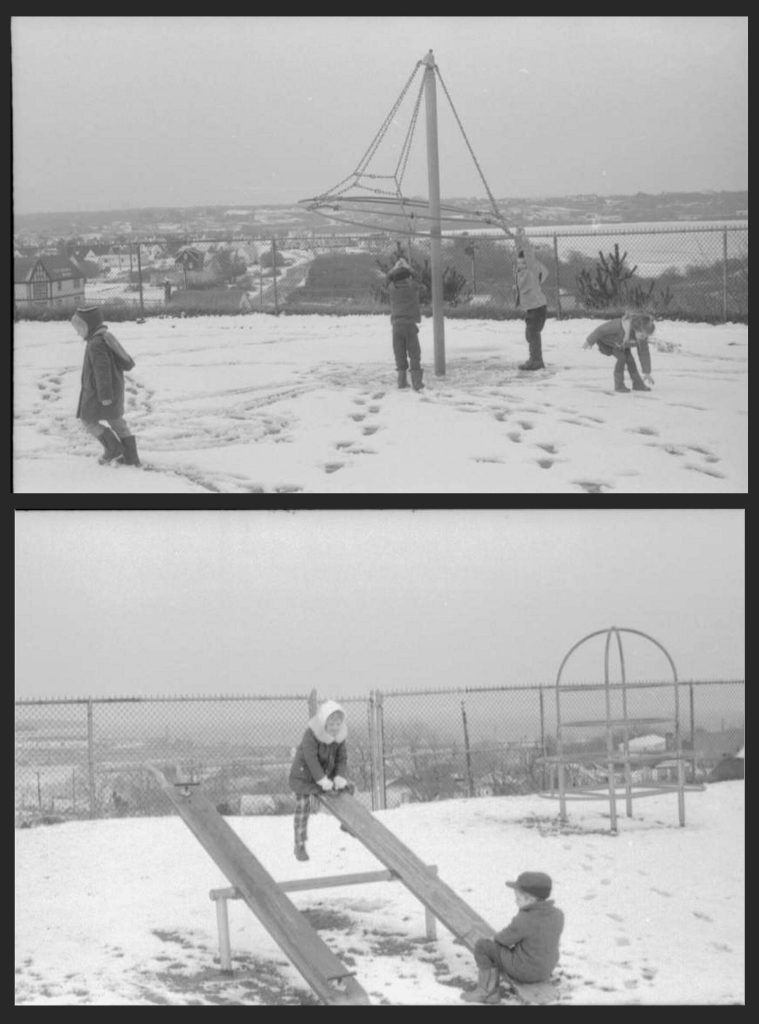 School age children playing with metal playground equipment in the snow photographed in black-and-white.