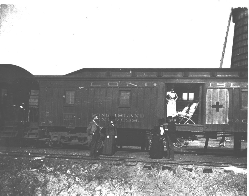 An old train car with nurses and a patient visible through an open door