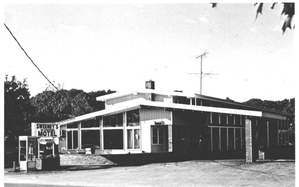One-story motel with sign and phone booth outside, circa 1970s.