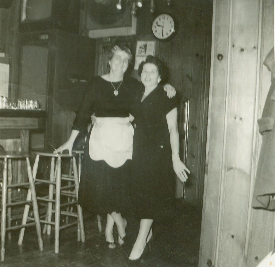 Tow women posing at the end of a old-fashioned bar.